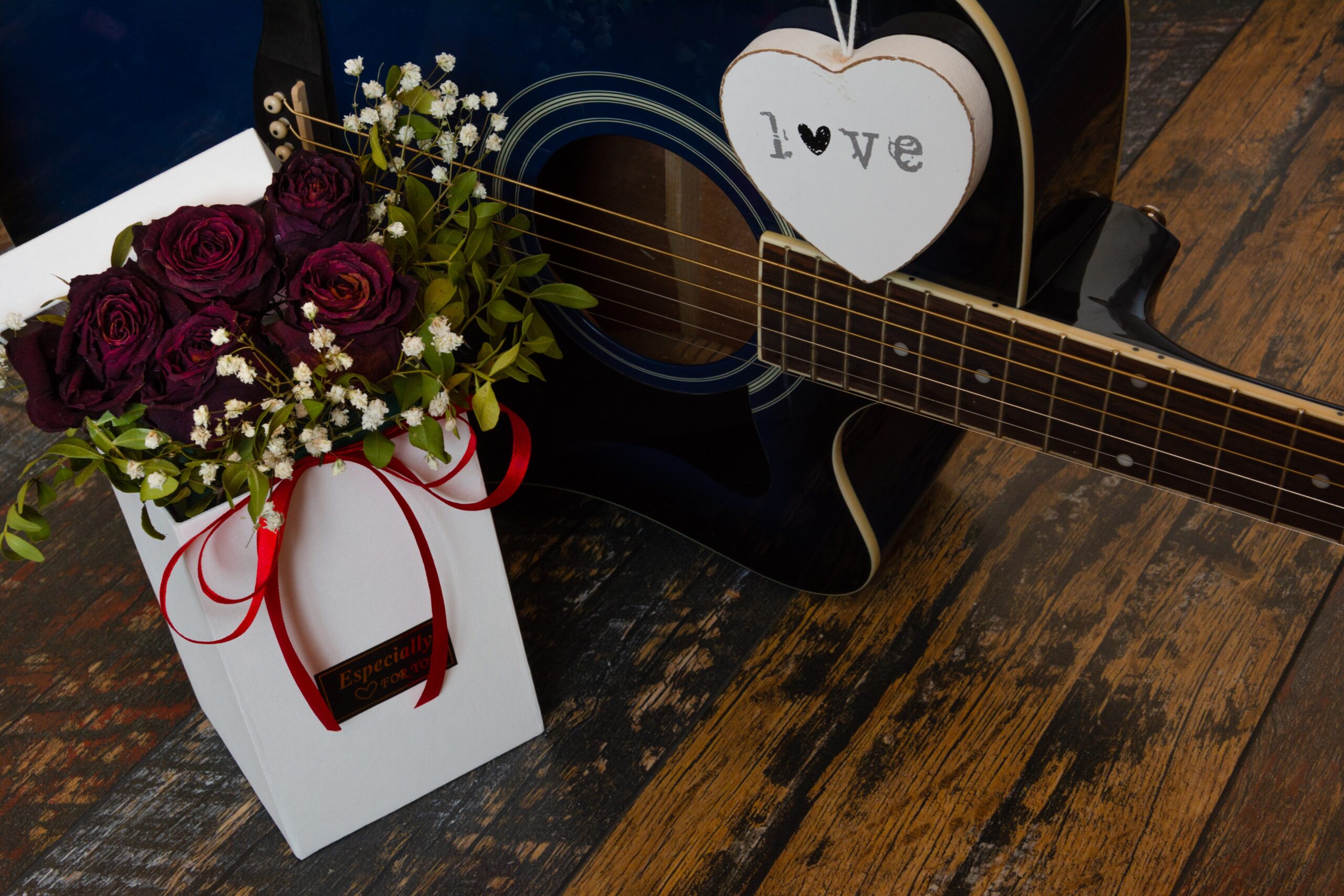 the picture of red roses and guitar is highlighting the theme of love in The Top 16 The Love Hypothesis Quotes by Ali HazelWood.