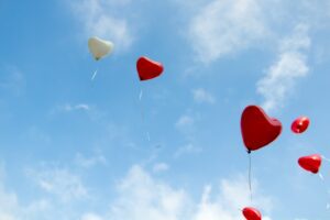 The is an image of a sky filled with red and white heart balloons. These balloons are indicating the beginning of romance. 