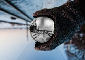 This is a picture of a man holding a ball that is showing reflection of the station that was only ours some time ago. 