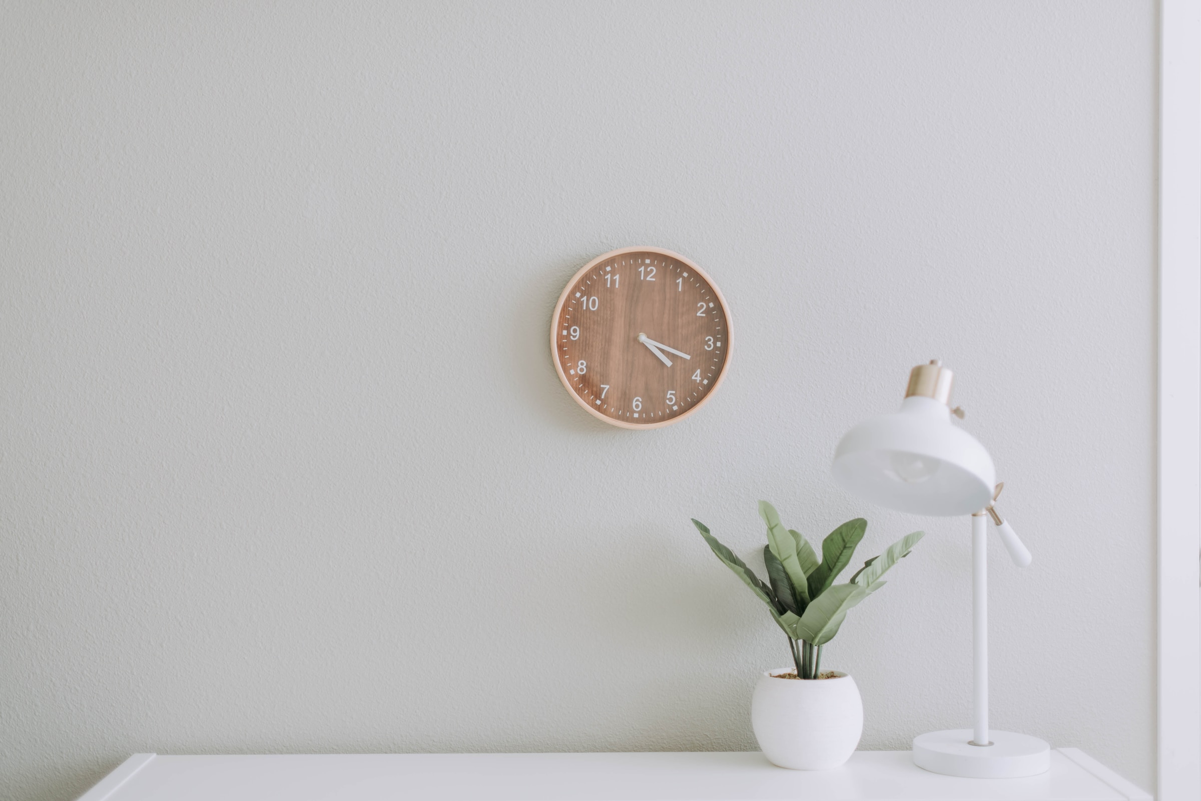 This is an image is of a whitewall decor: a lamp, a vase, and clock, explaining what is minimalism.