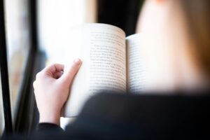 This is an image of girl holding and reading a book based on romance. 