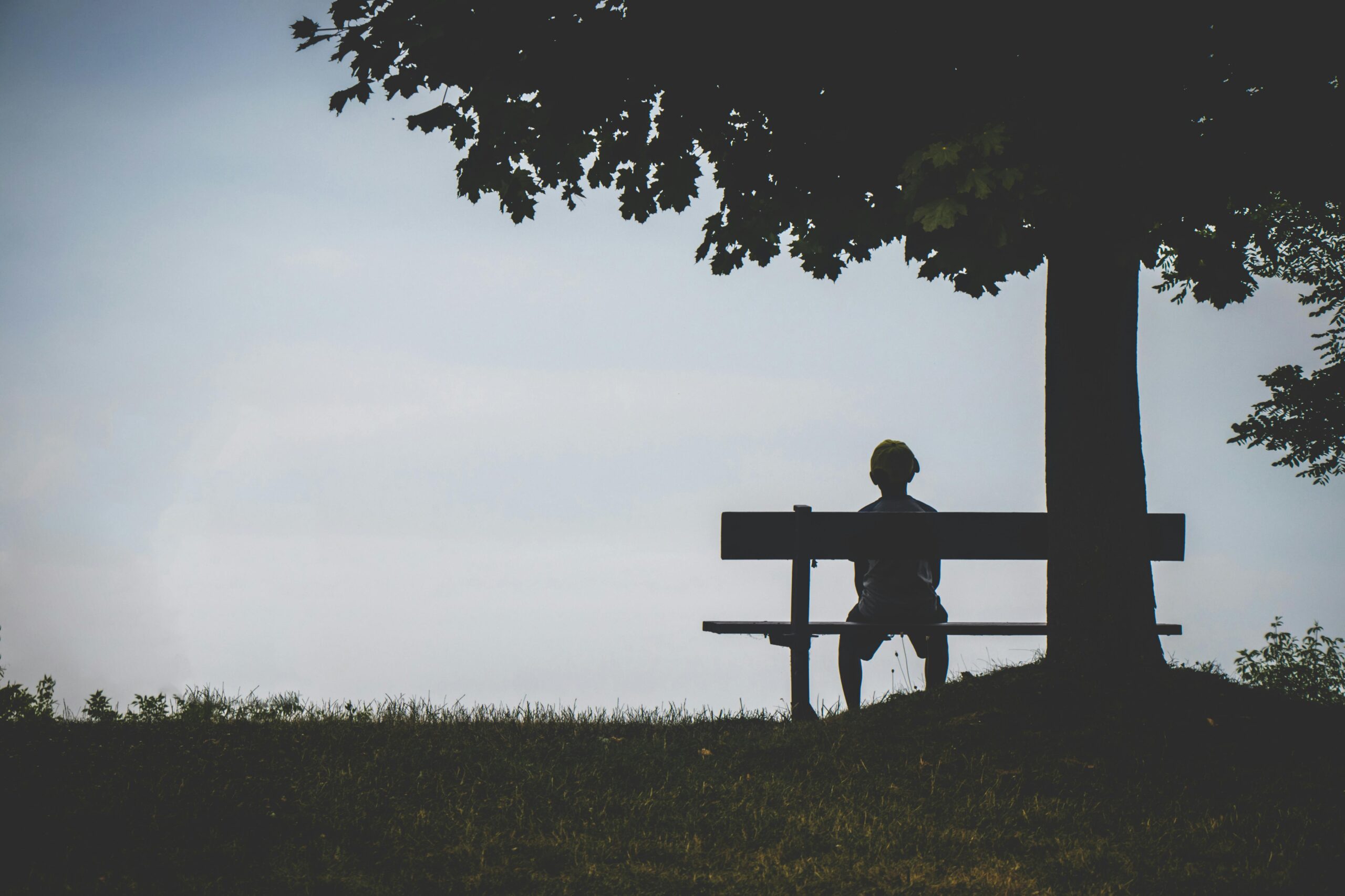 This is an image of a man sitting on a bench, showing theme of isolation in Existentialism Quotes.
